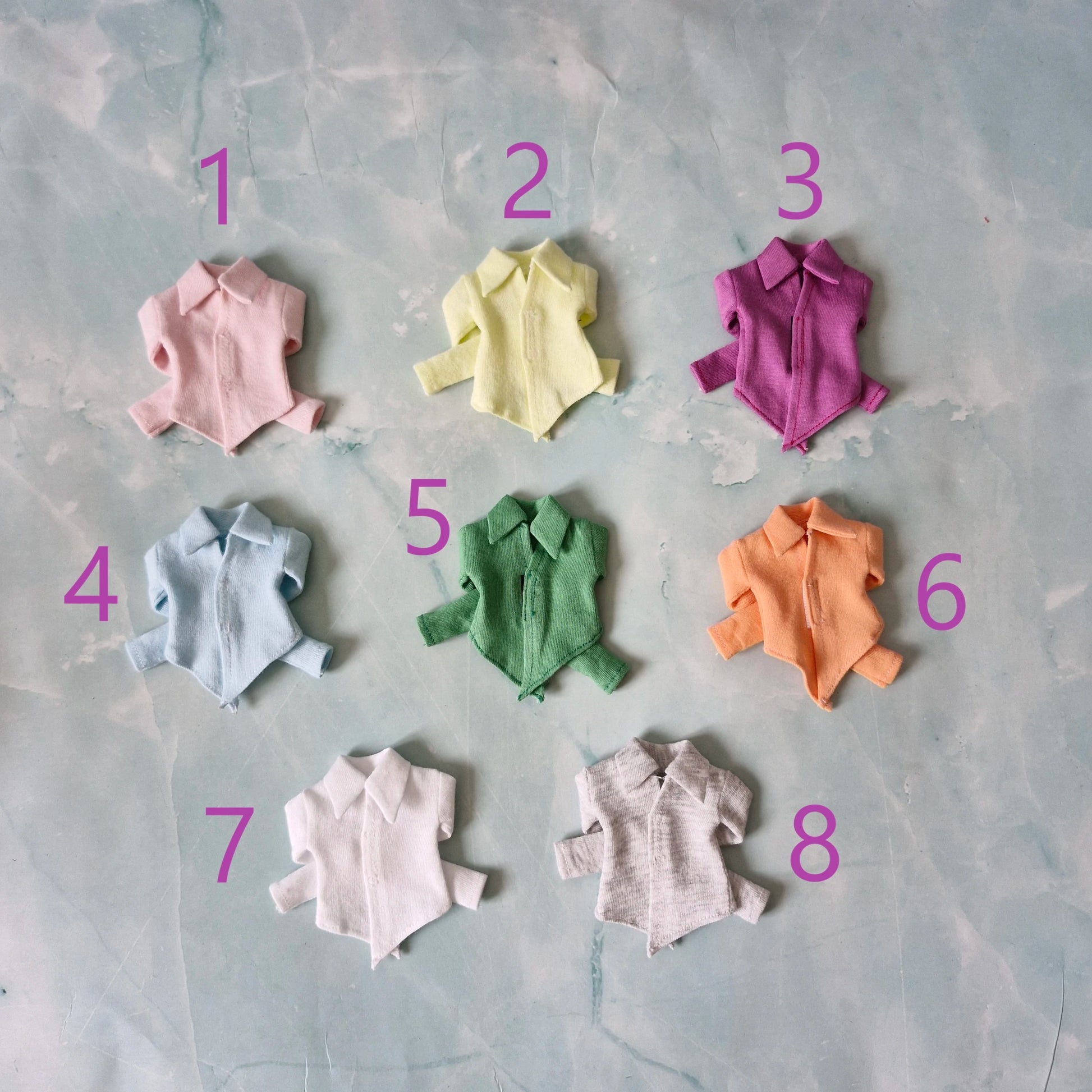 Collection of 8 doll pointed hem shirts in colors light pink, yellow, magenta, light blue, green, peach, white, and grey.