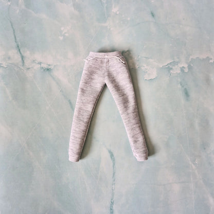 Flat lay of grey heathered doll sweatpants with an elastic waistband, white drawstrings, and cuffed ankles.