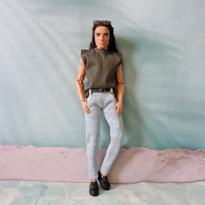 Full body view of a Ken doll styling an olive sleeveless shirt, light blue jeans, and black loafers.