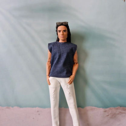 Close-up of a long-haired Ken doll wearing a stylish navy sleeveless top and white ripped pants.