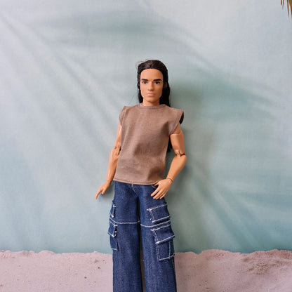 Ken doll posing in a brown sleeveless tee and dark blue baggy cargo jeans with white stitching details.