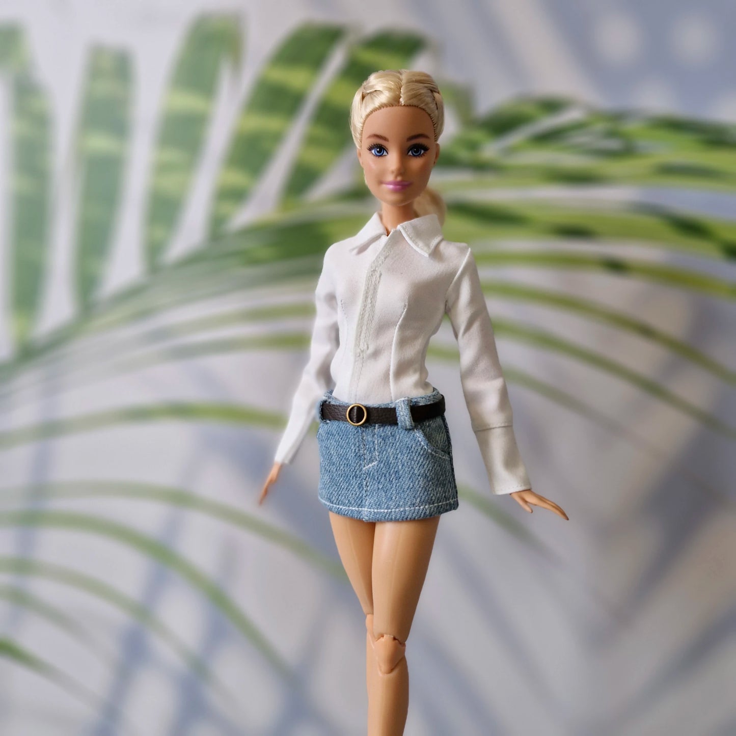 Fashionable Barbie doll dressed in a tailored white long-sleeve shirt and blue jean mini skirt.