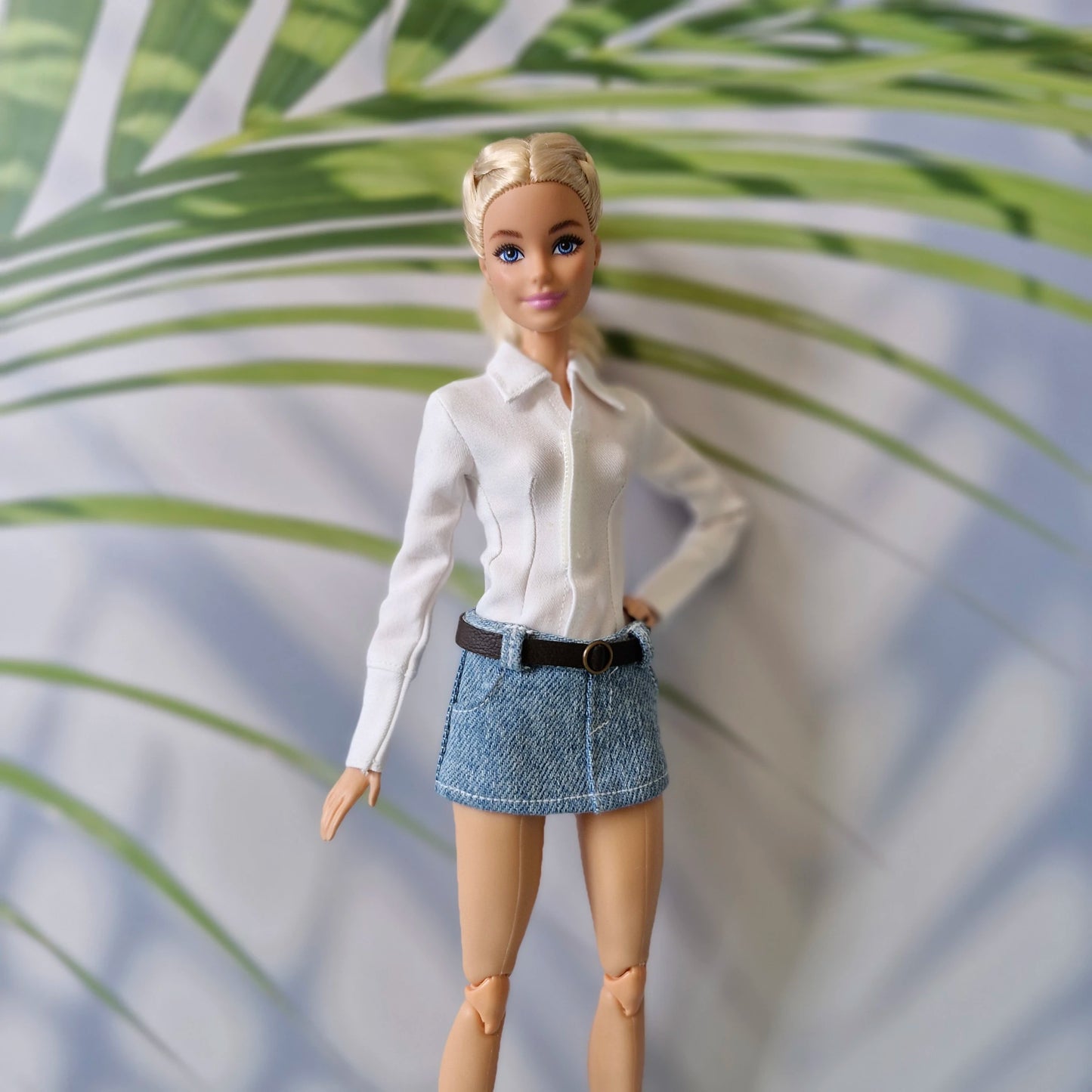 Barbie doll showcasing a versatile everyday outfit with a white long-sleeve shirt and belted denim skirt.
