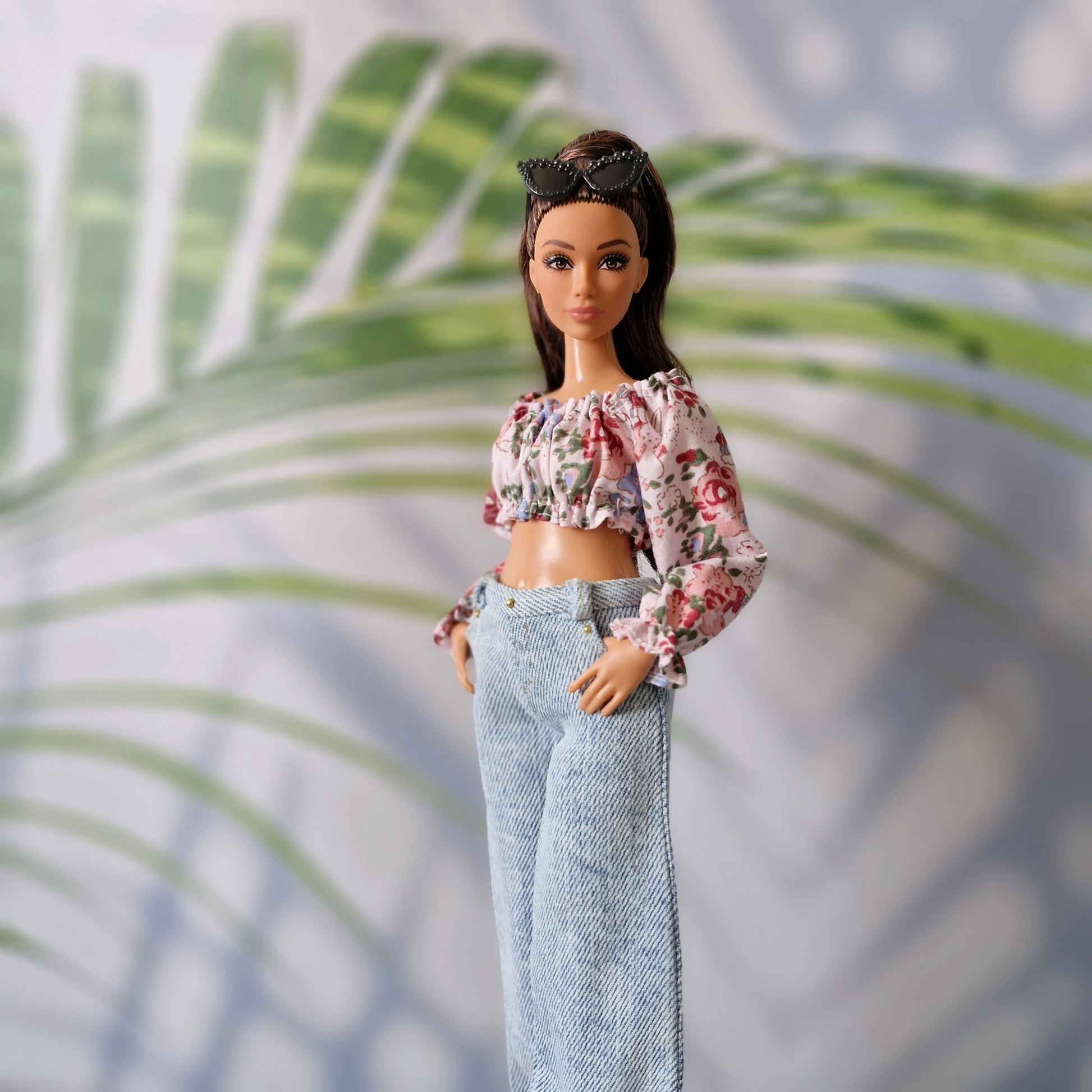 Curvy Barbie modeling a relaxed summer look with a floral ruffle shirt and light wash high-waisted denim.