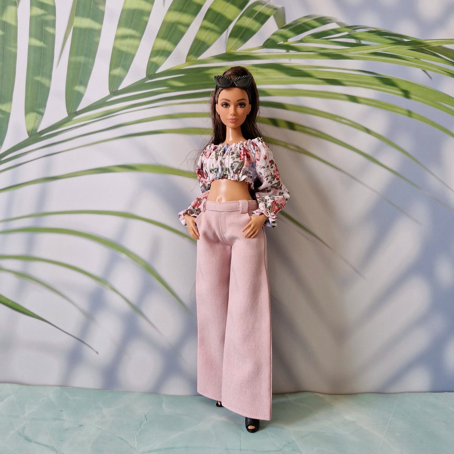 Full body shot of a Curvy Barbie doll showcasing a floral long-sleeve crop top paired with pastel pink wide-leg pants.