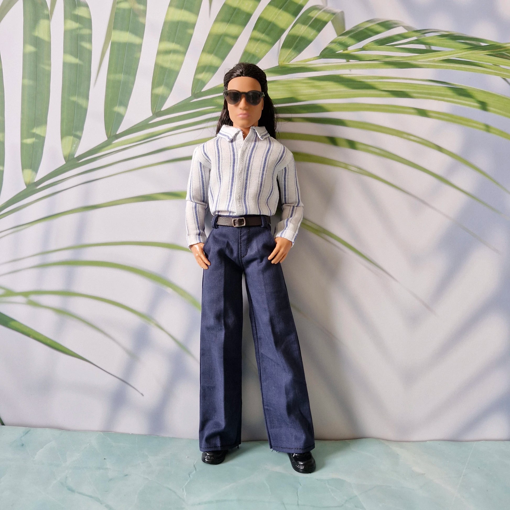 Ken doll wearing black sunglasses, a stylish striped button-down shirt, and tailored navy pants.