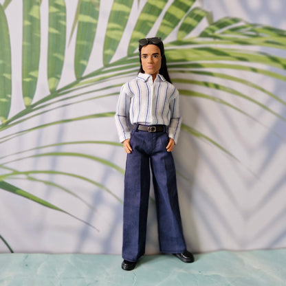 Ken doll fashion featuring a smart-casual look with a tucked-in striped shirt and navy trousers, standing with hands in pockets.