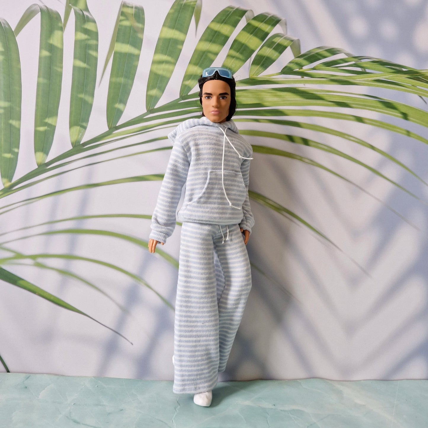 Ken doll styling a casual loungewear look with a striped hoodie and matching wide-leg pants.