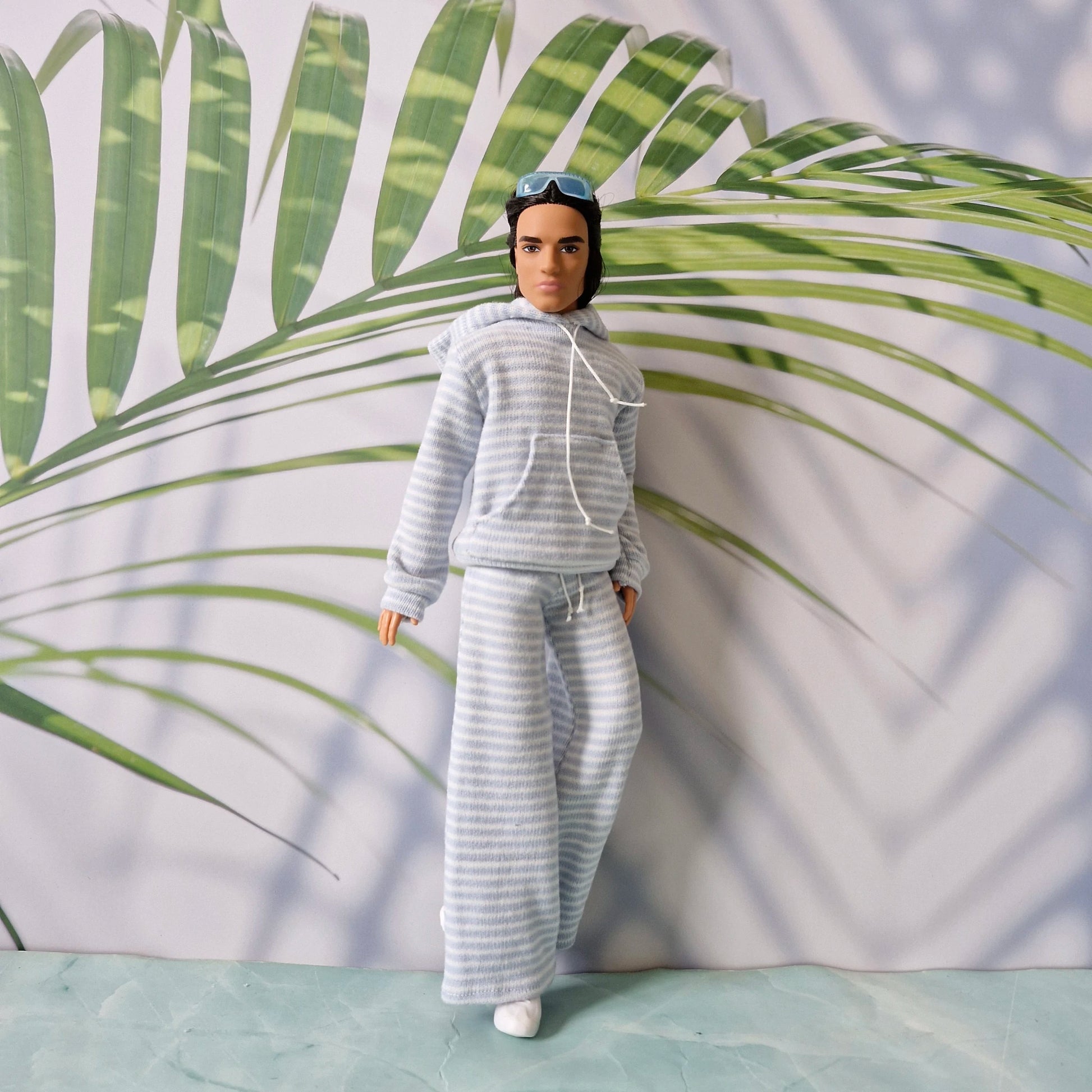 Ken doll styling a casual loungewear look with a striped hoodie and matching wide-leg pants.
