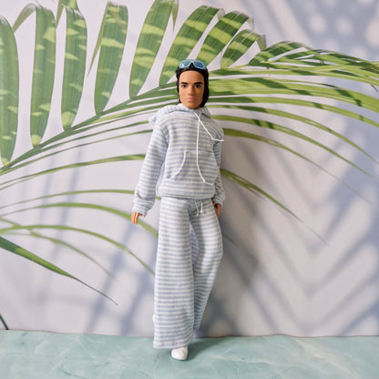 Ken doll styling a casual loungewear look with a striped hoodie and matching wide-leg pants.