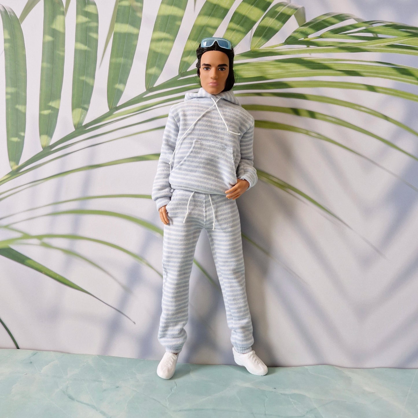 Front view of Ken doll modeling a casual striped loungewear set including a hoodie and joggers.