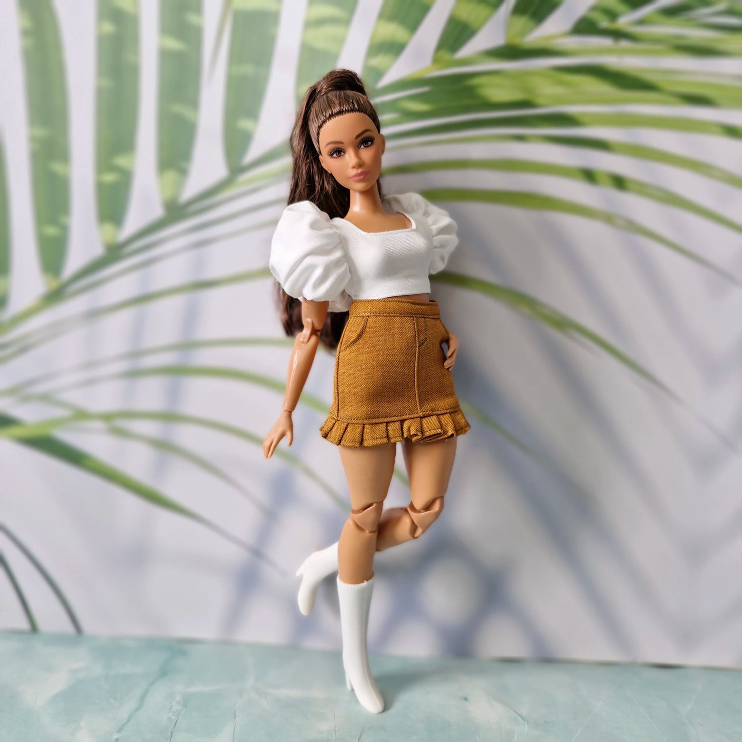Trendy Barbie doll fashion showing a white square-neck puff-sleeve top paired with a brown ruffled hem skirt.