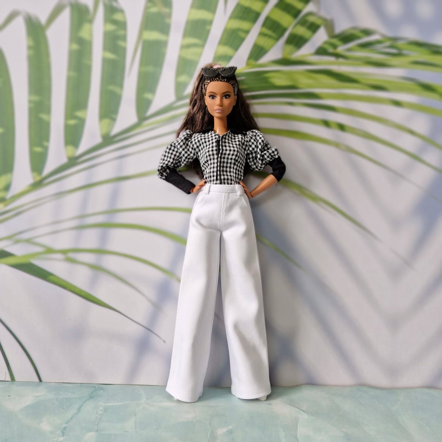 Full body view of a fashion doll wearing casual clothes for Barbie with a checkered top and elegant white trousers.