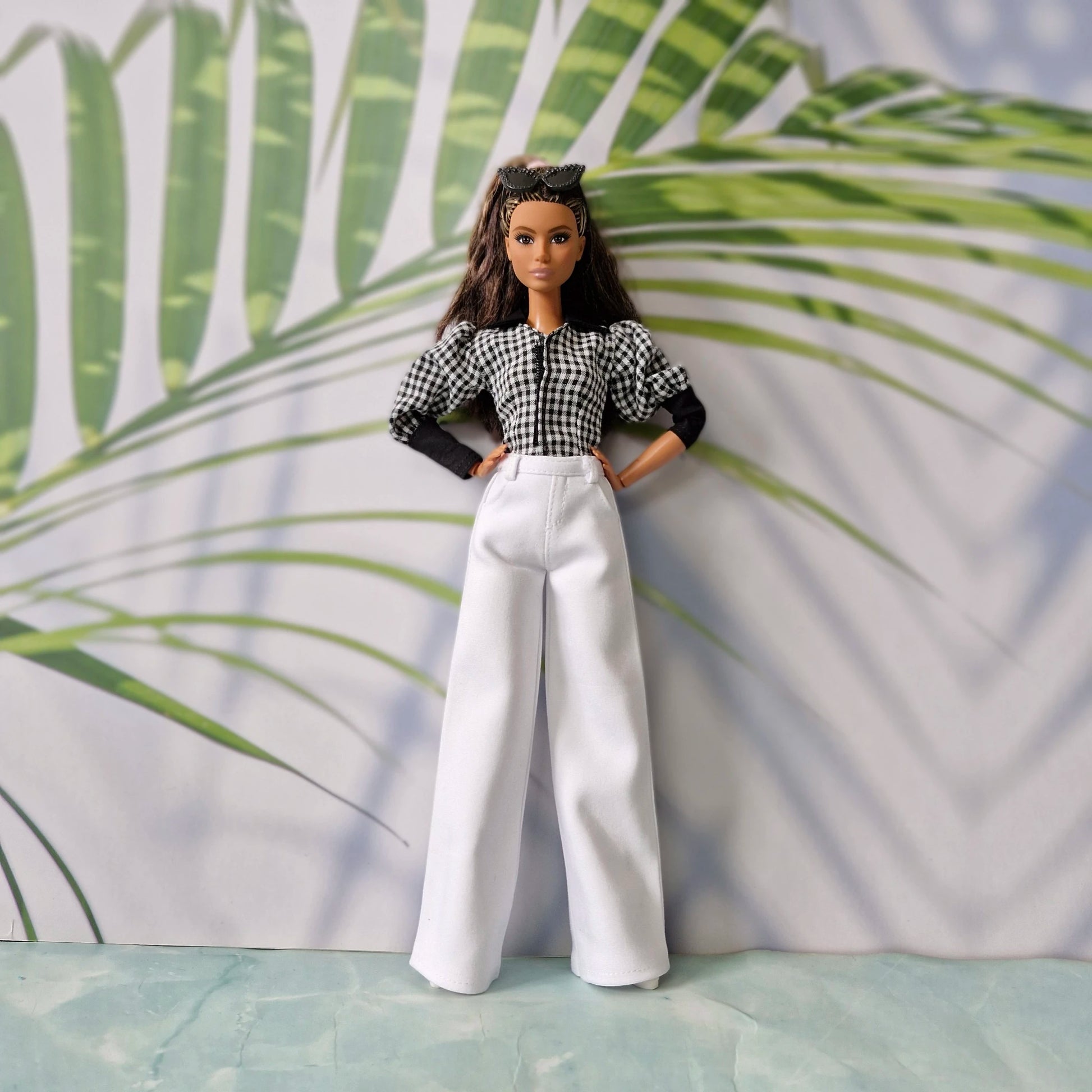 Full body view of a fashion doll wearing casual clothes for Barbie with a checkered top and elegant white trousers.