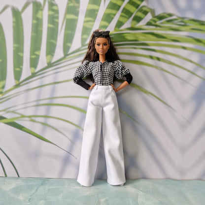 Full body view of a fashion doll wearing casual clothes for Barbie with a checkered top and elegant white trousers.