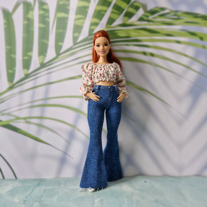Redhead doll with hands in pockets wearing a pink floral blouse and dark wash flared jeans for Curvy Barbie.