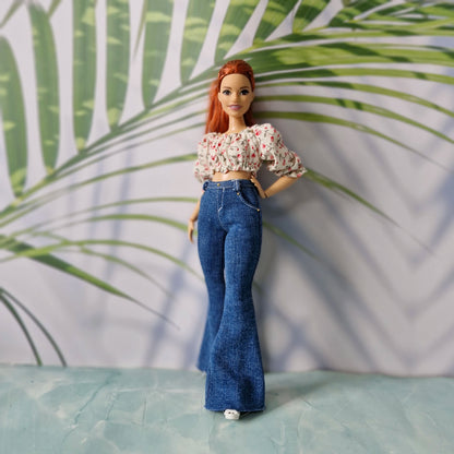Curvy doll modeling trendy clothes for Curvy Barbie, featuring a pink floral puff-sleeve top and dark denim bell-bottoms.