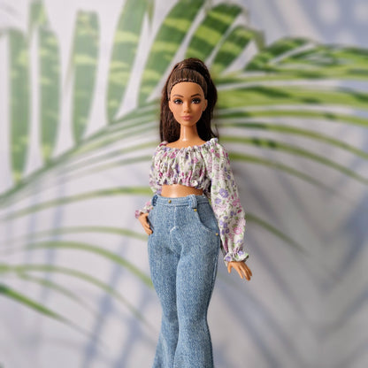Brunette fashion doll wearing a purple floral crop top and light blue flared denim jeans for Curvy Barbie.