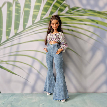 Full body shot of a doll in stylish casual clothes for Curvy Barbie, including a purple floral top and light wash jeans.