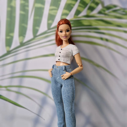 Redhead fashion doll modeling a grey short-sleeve button crop top and light blue denim jeans for Curvy Barbie.