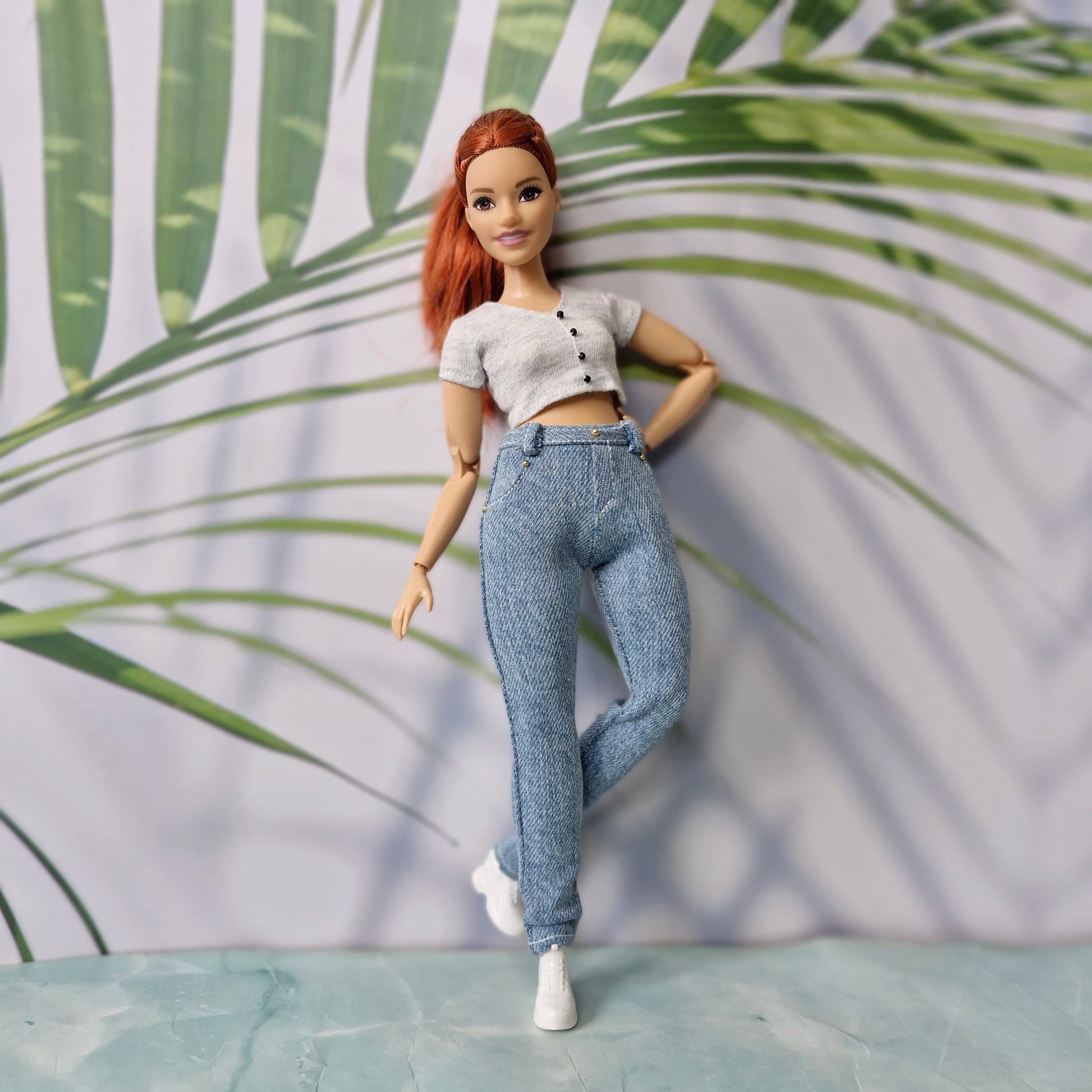 Full body shot of a redhead curvy doll showcasing a chic grey top and light skinny jeans for Curvy Barbie.