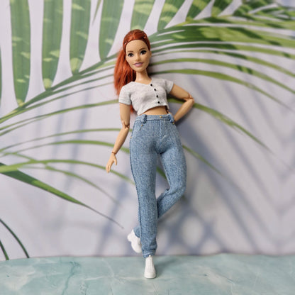 Full body shot of a redhead curvy doll showcasing a chic grey top and light skinny jeans for Curvy Barbie.