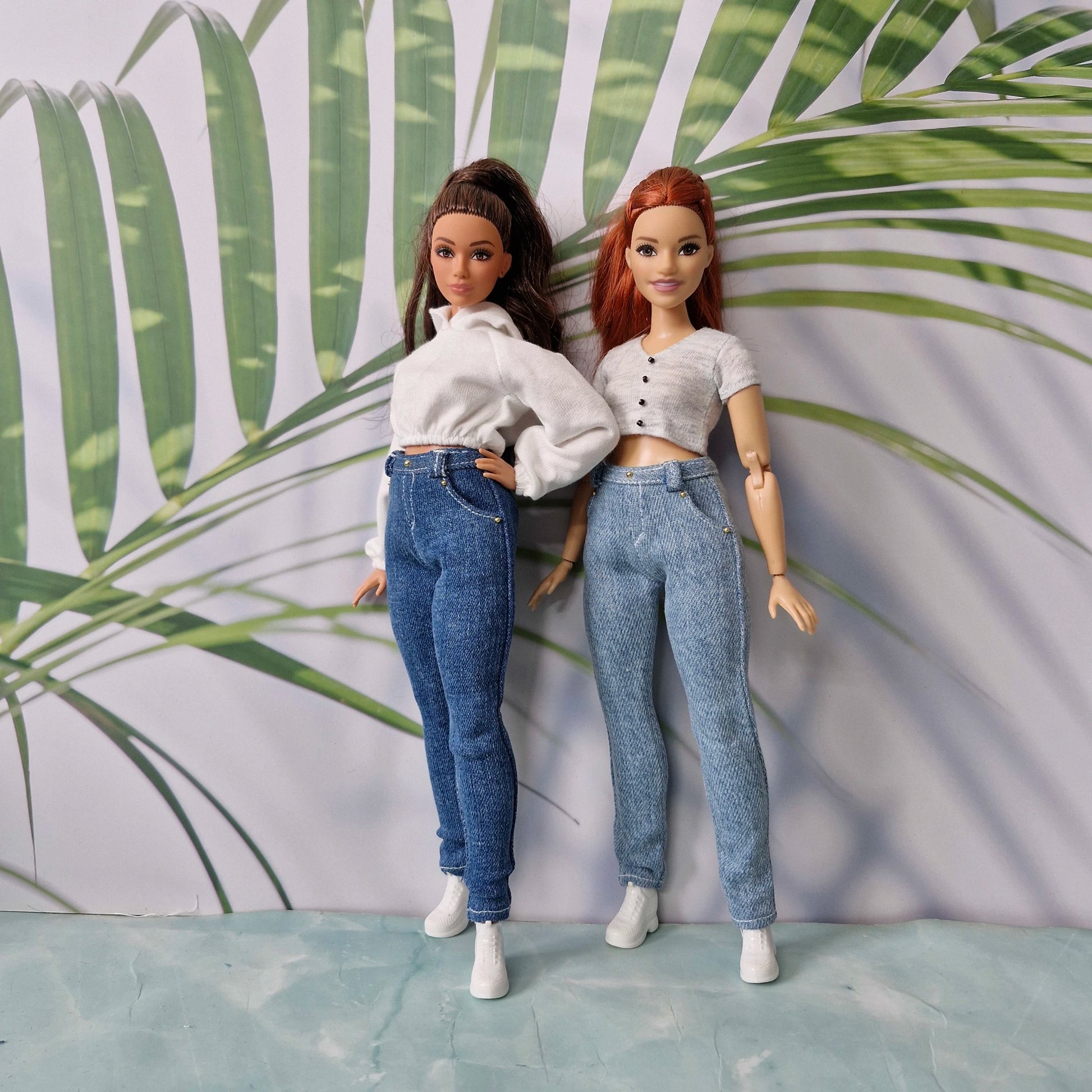 Two curvy dolls standing side by side modeling casual tops and skinny jeans outfits for Curvy Barbie.