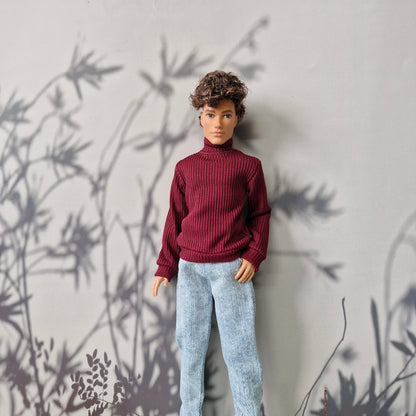 Close-up of a doll dressed in a burgundy long-sleeve turtleneck and casual jeans for Ken.