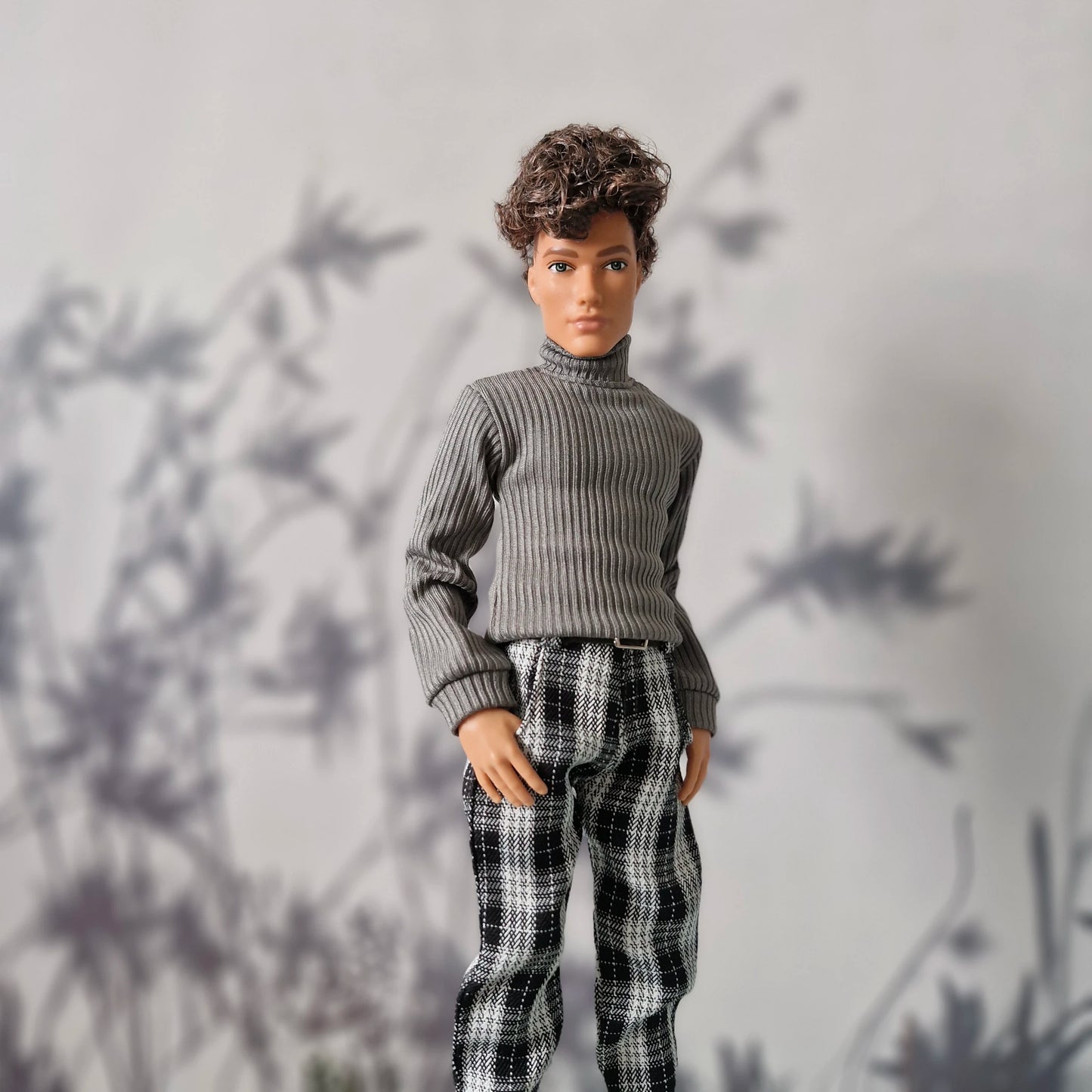 Trendy winter clothes for Ken featuring a grey ribbed sweater and black plaid trousers.