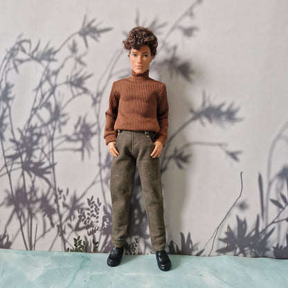 Ken doll dressed in a brown ribbed sweater, plain olive green pants, and black loafers for Ken.