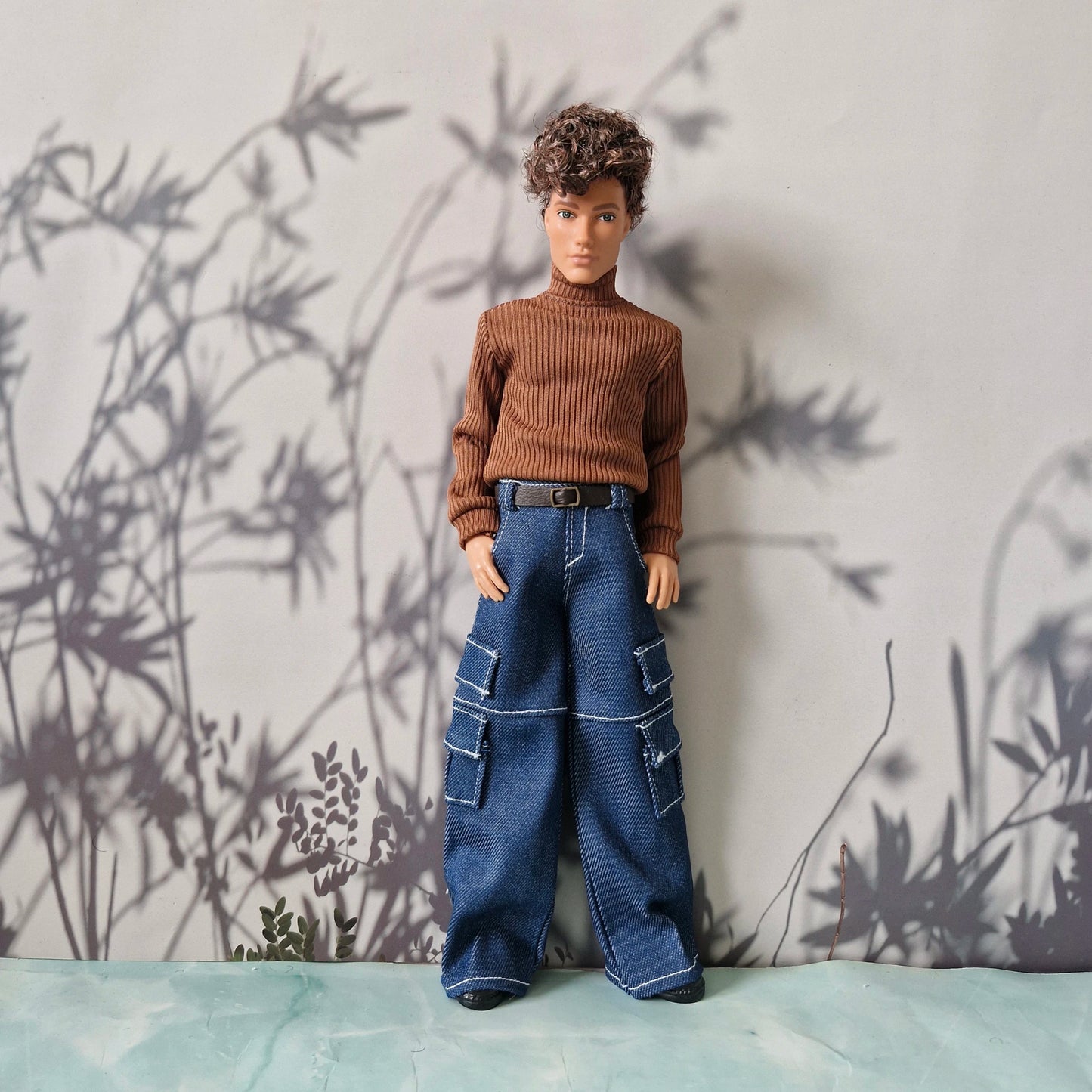 Ken doll modeling a brown long-sleeve turtleneck sweater and blue denim cargo pants for Ken.