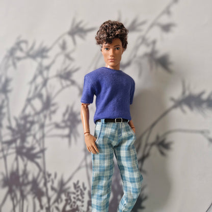 Close-up of a male doll wearing a blue t-shirt and stylish blue plaid pants for Ken.