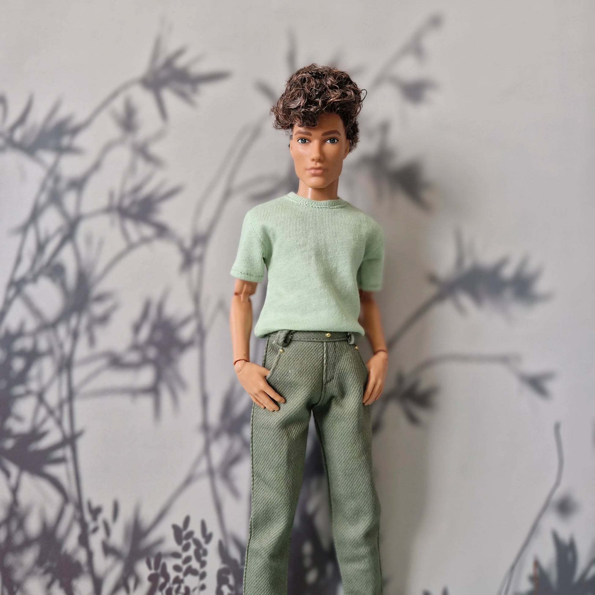 Ken doll modeling a mint green short-sleeve t-shirt and solid olive green pants for Ken.