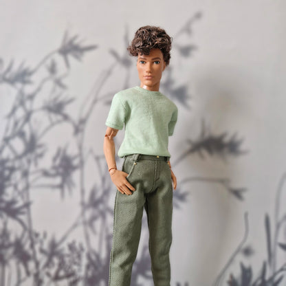 Close up of a mint green short-sleeve top and solid olive green pants for Ken.