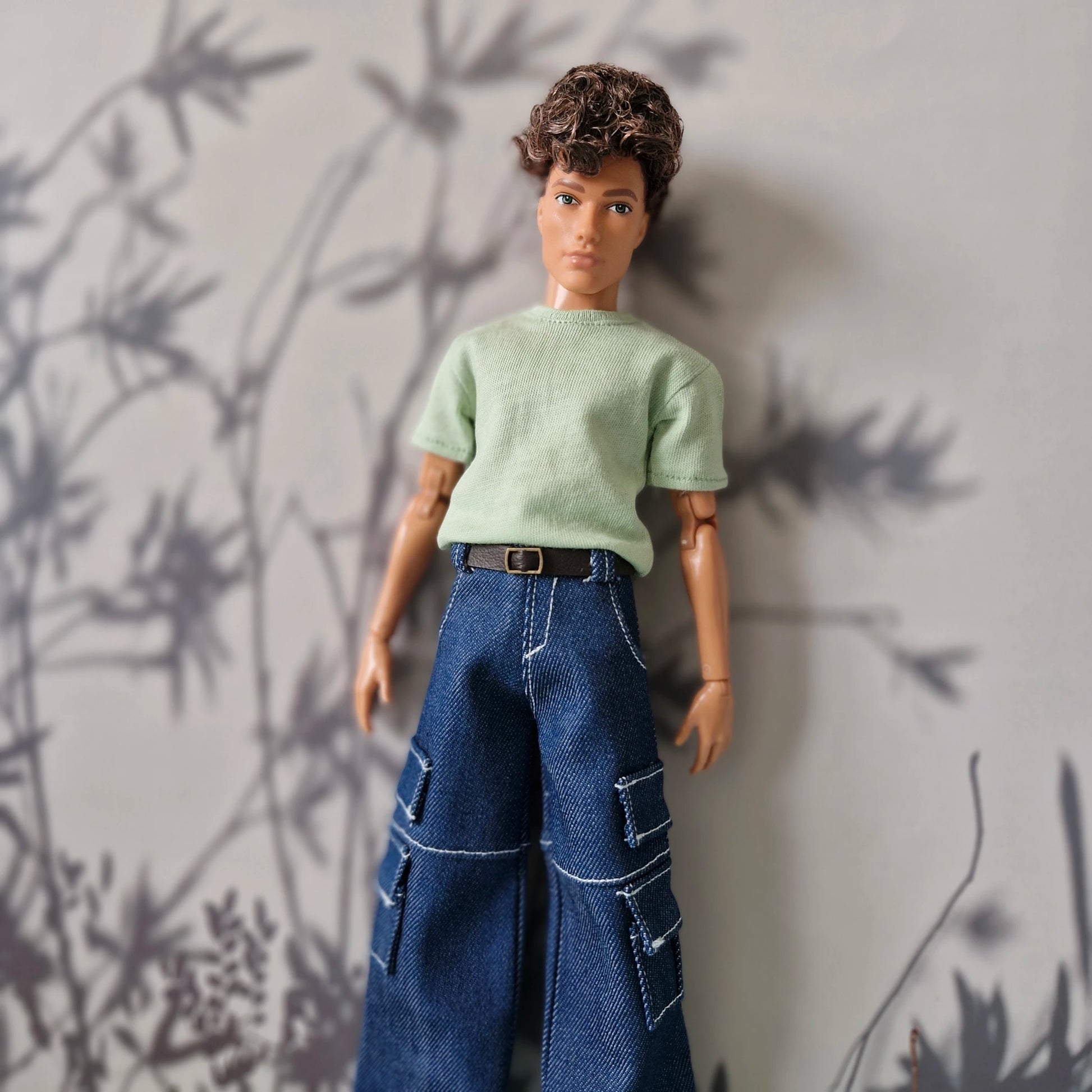 Ken doll wearing a casual light green short-sleeve t-shirt and blue denim cargo pants for Ken.