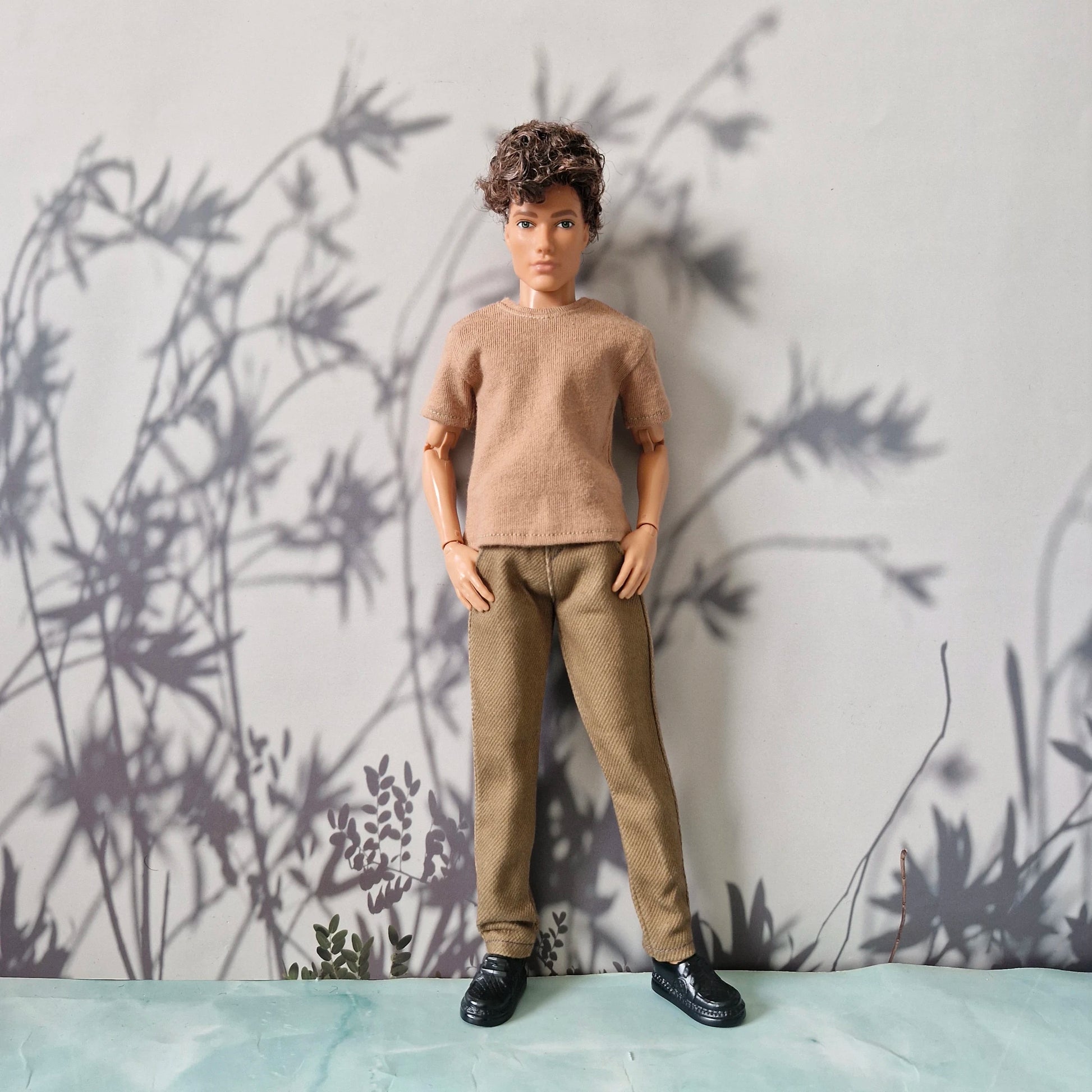 Doll dressed in a beige short-sleeve t-shirt and plain khaki tan pants for Ken.