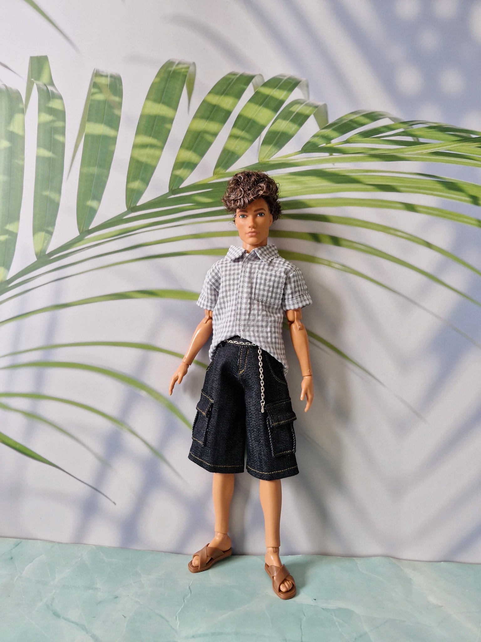 1/6 scale fashion doll wearing a grey gingham short-sleeve shirt and dark denim cargo shorts tailored for Ken.