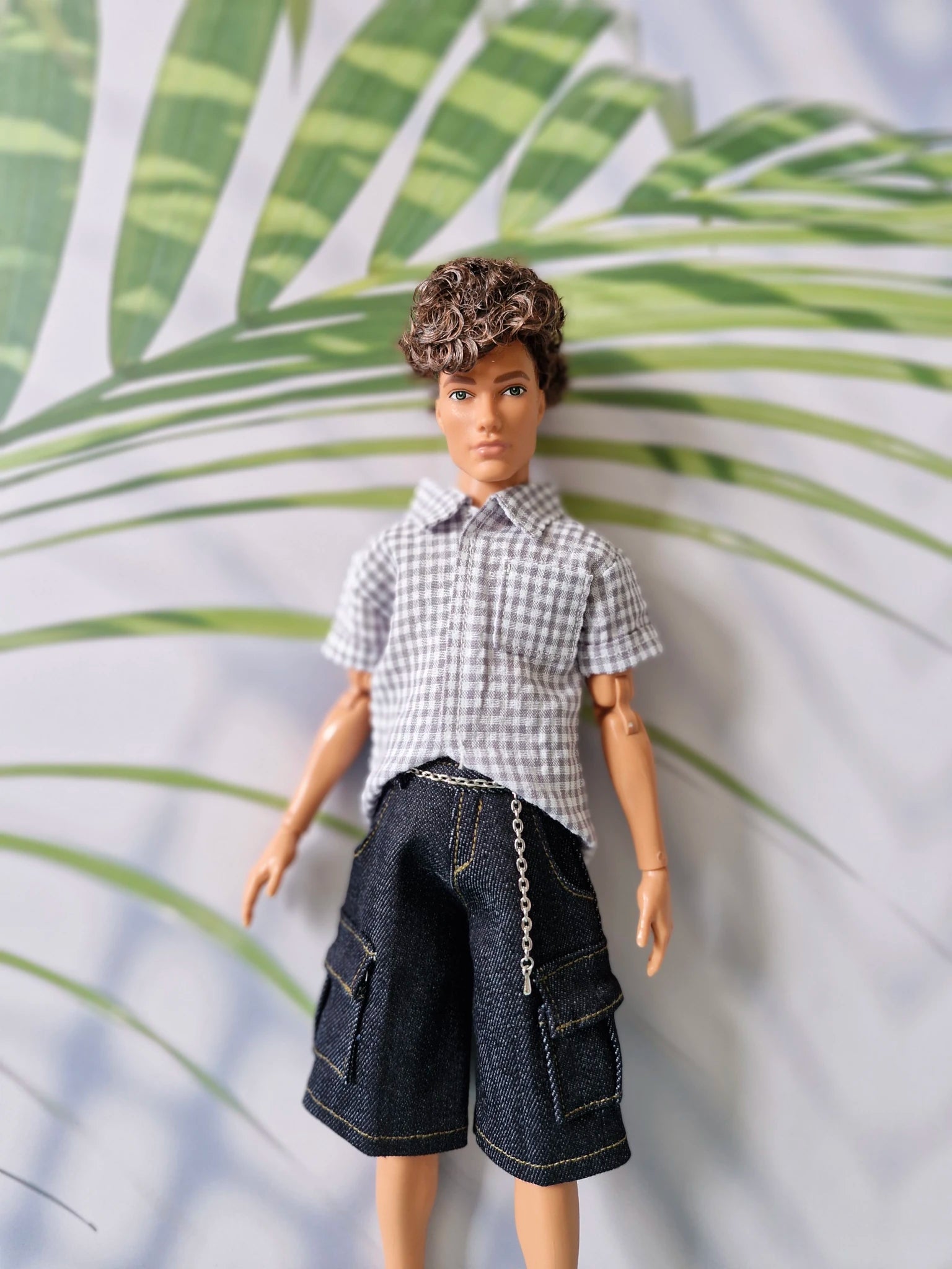 Close up of a 1/6 scale male doll modeling a casual grey gingham shirt and dark denim pocket shorts for Ken.