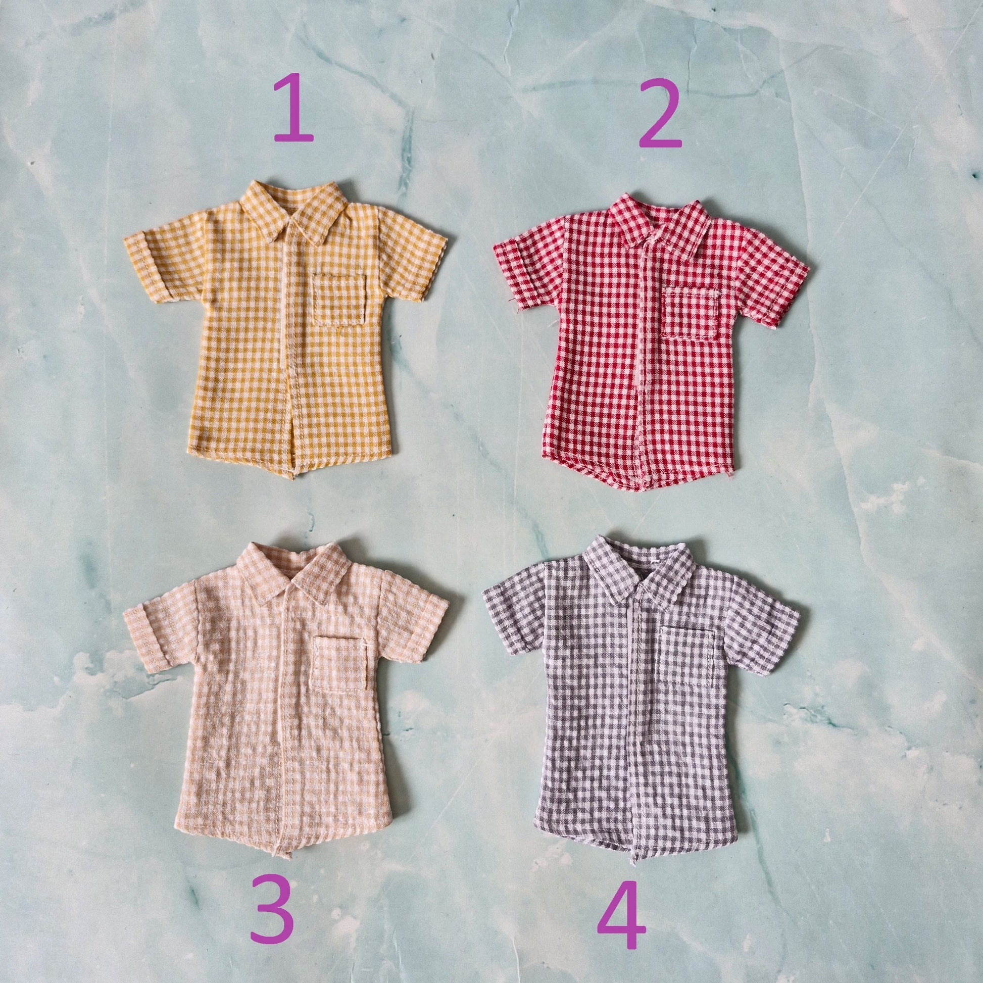 Flat lay of four 1/6 scale doll gingham shirts in yellow, red, beige, and grey sold separately for Ken.