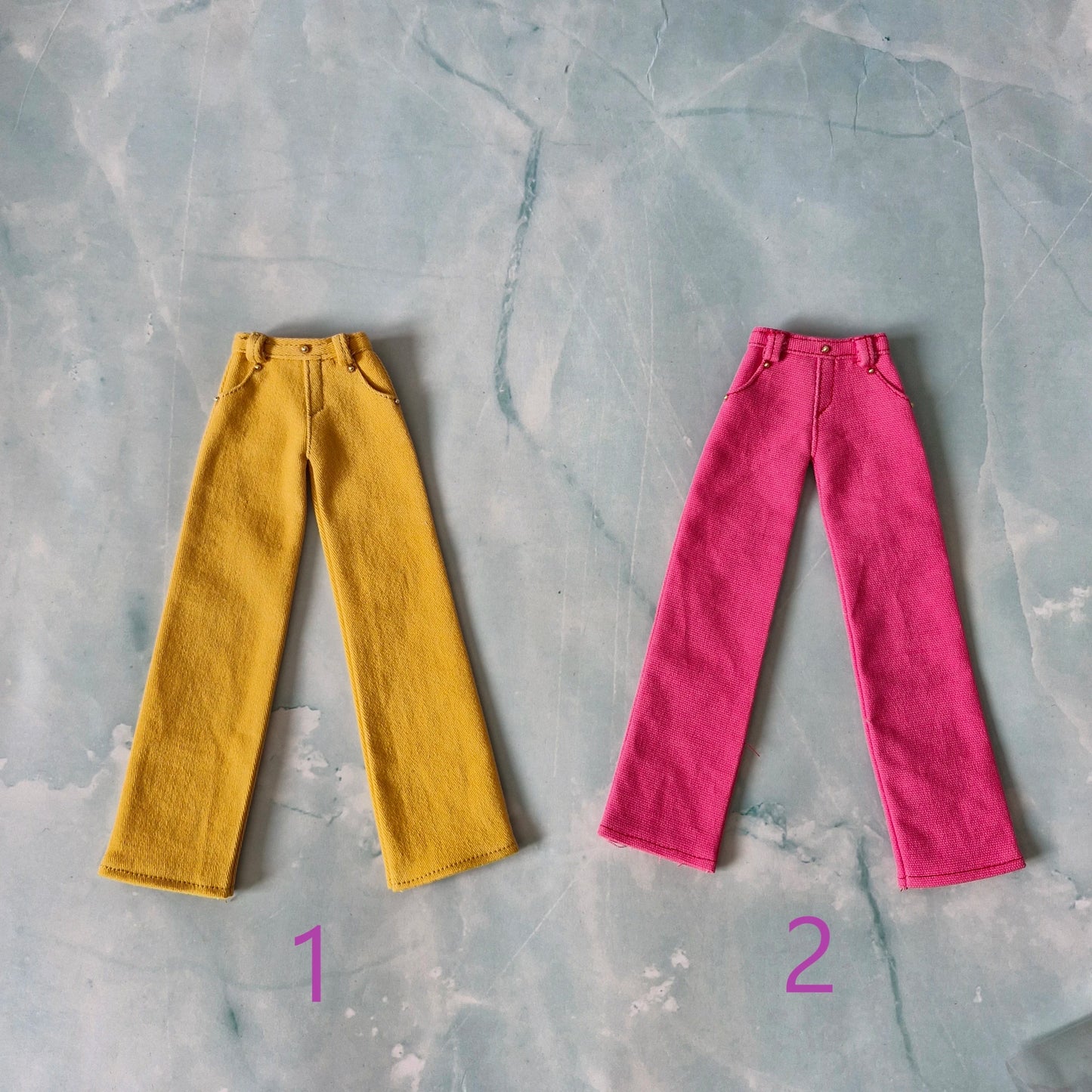 Flat lay of two 1/6 scale wide-leg doll pants in yellow and dark pink sold separately.