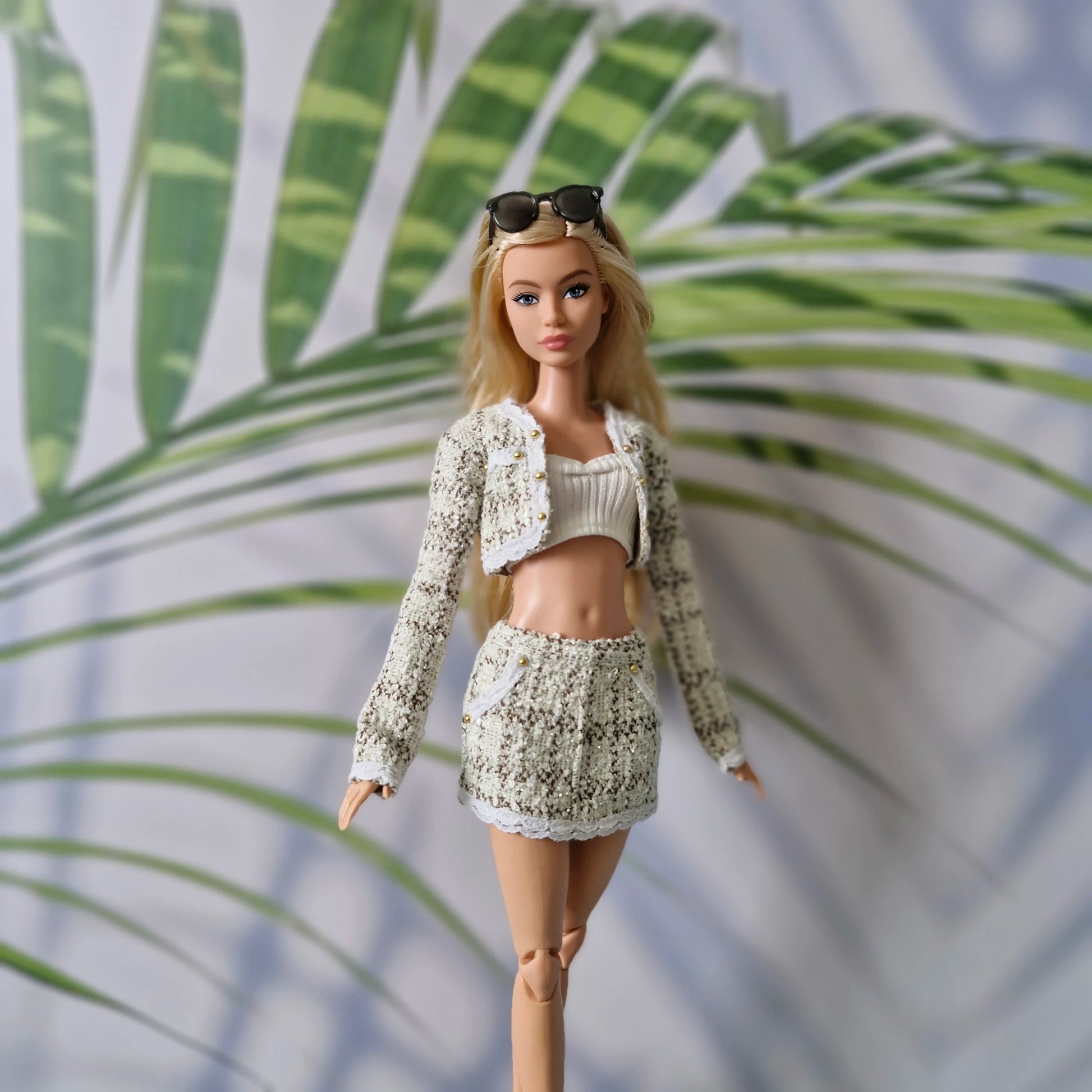 11.5 inch fashion doll wearing a chic cream tweed 3-piece skirt set for Barbie against a tropical palm background.