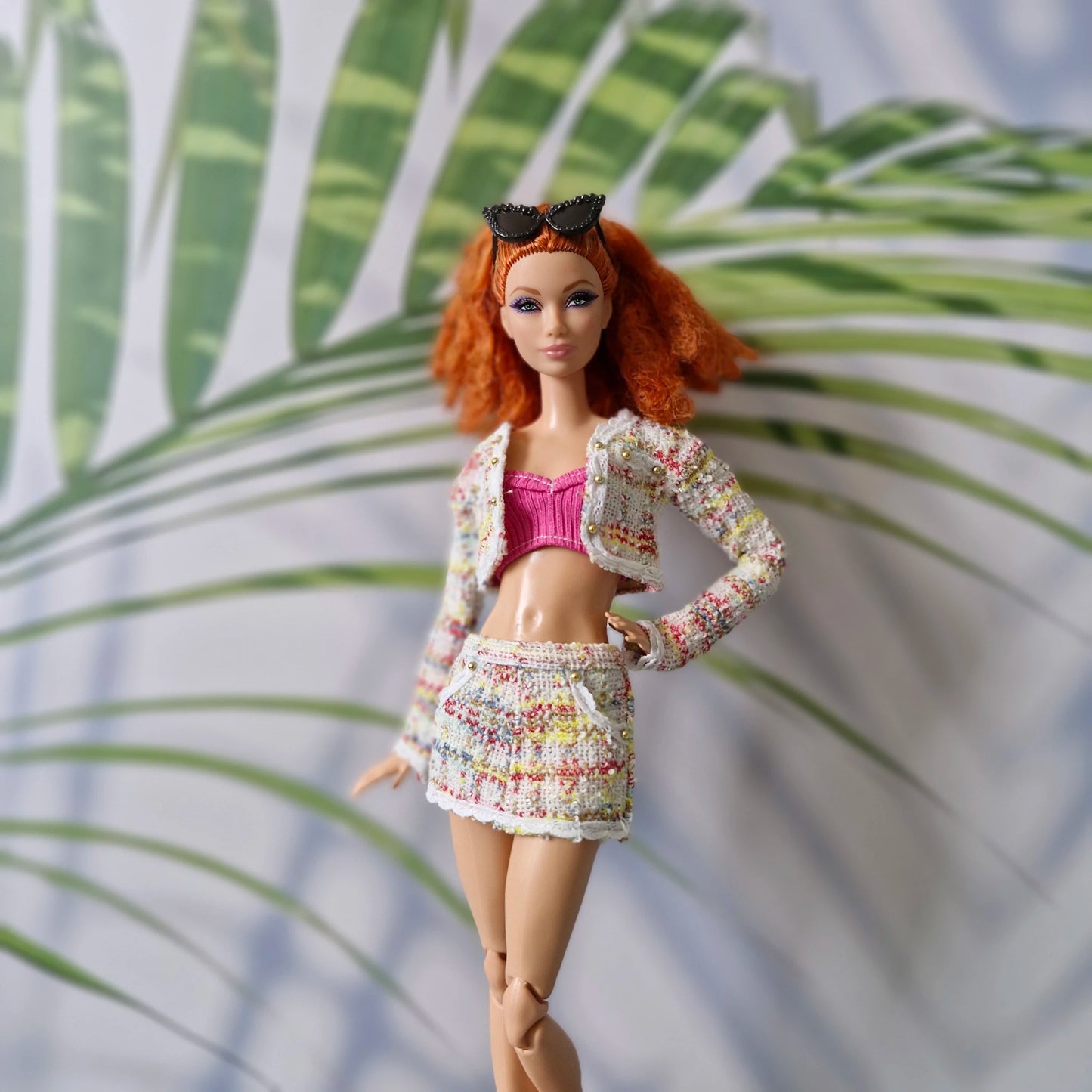 Curvy doll modeling a colorful multicolor tweed cropped jacket and matching skirt outfit for Barbie with a pink top.