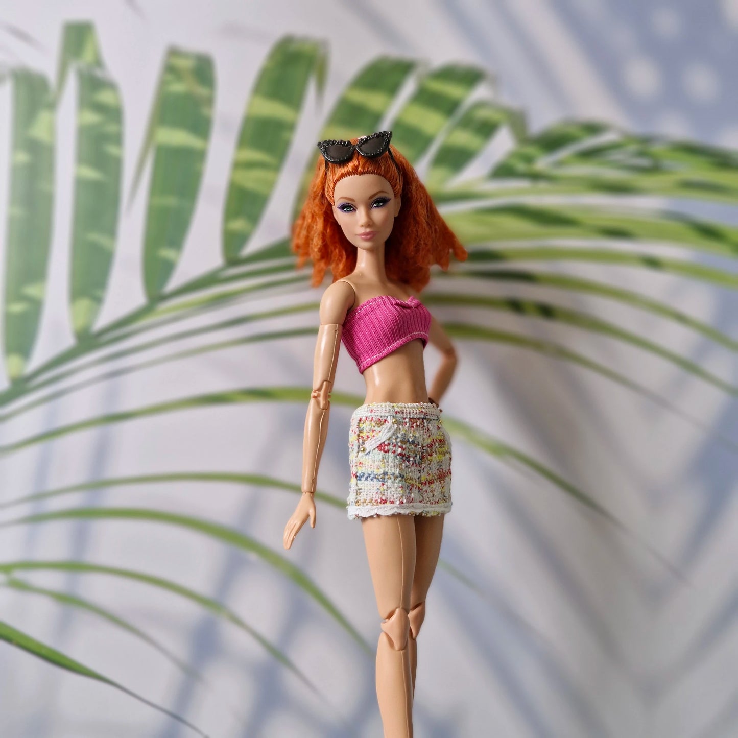 11.5 inch fashion doll modeling a pink crop top and tweed skirt for Barbie paired with black sunglasses.