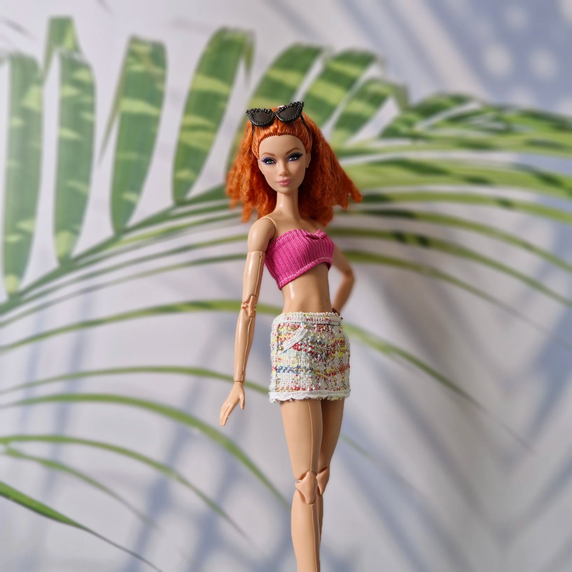 11.5 inch fashion doll modeling a pink crop top and tweed skirt for Barbie paired with black sunglasses.