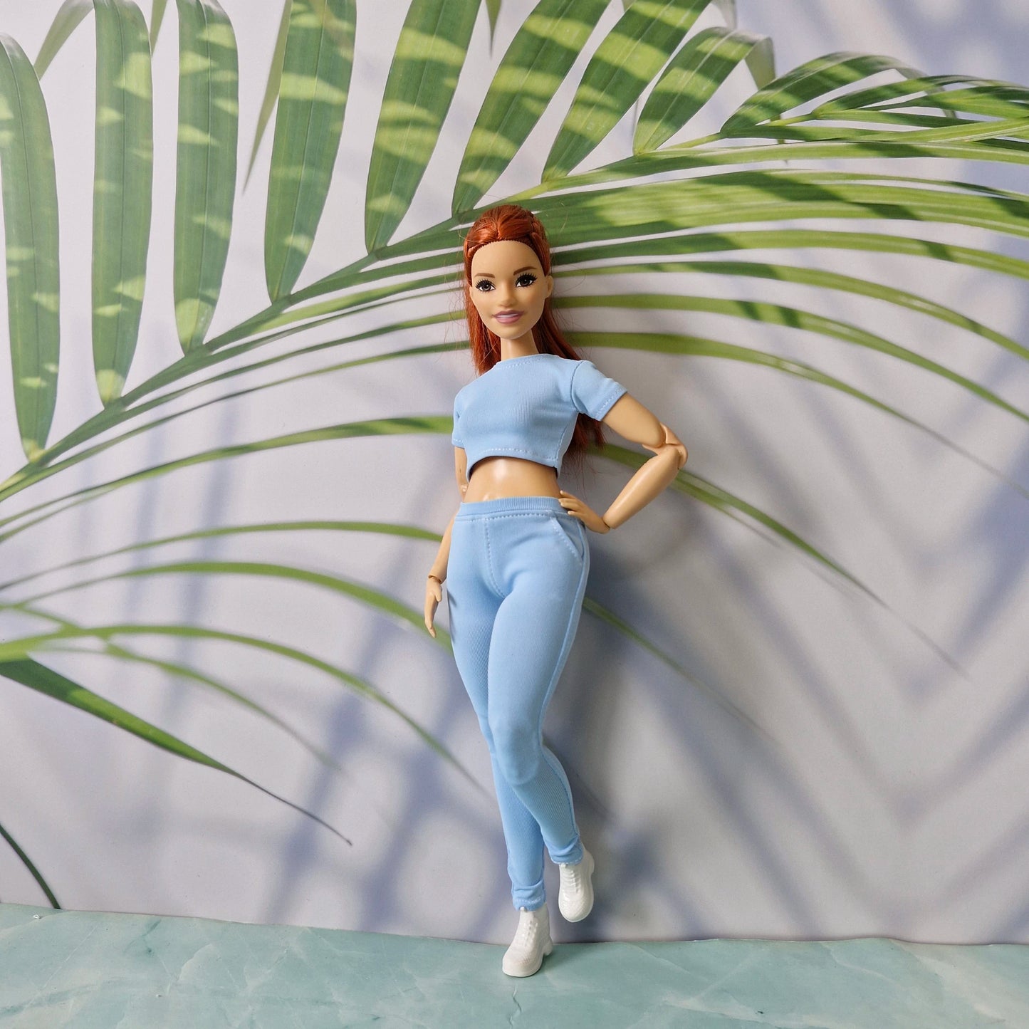 11.5 inch fashion doll modeling a light blue ribbed crop top and pants sold separately for Barbie.