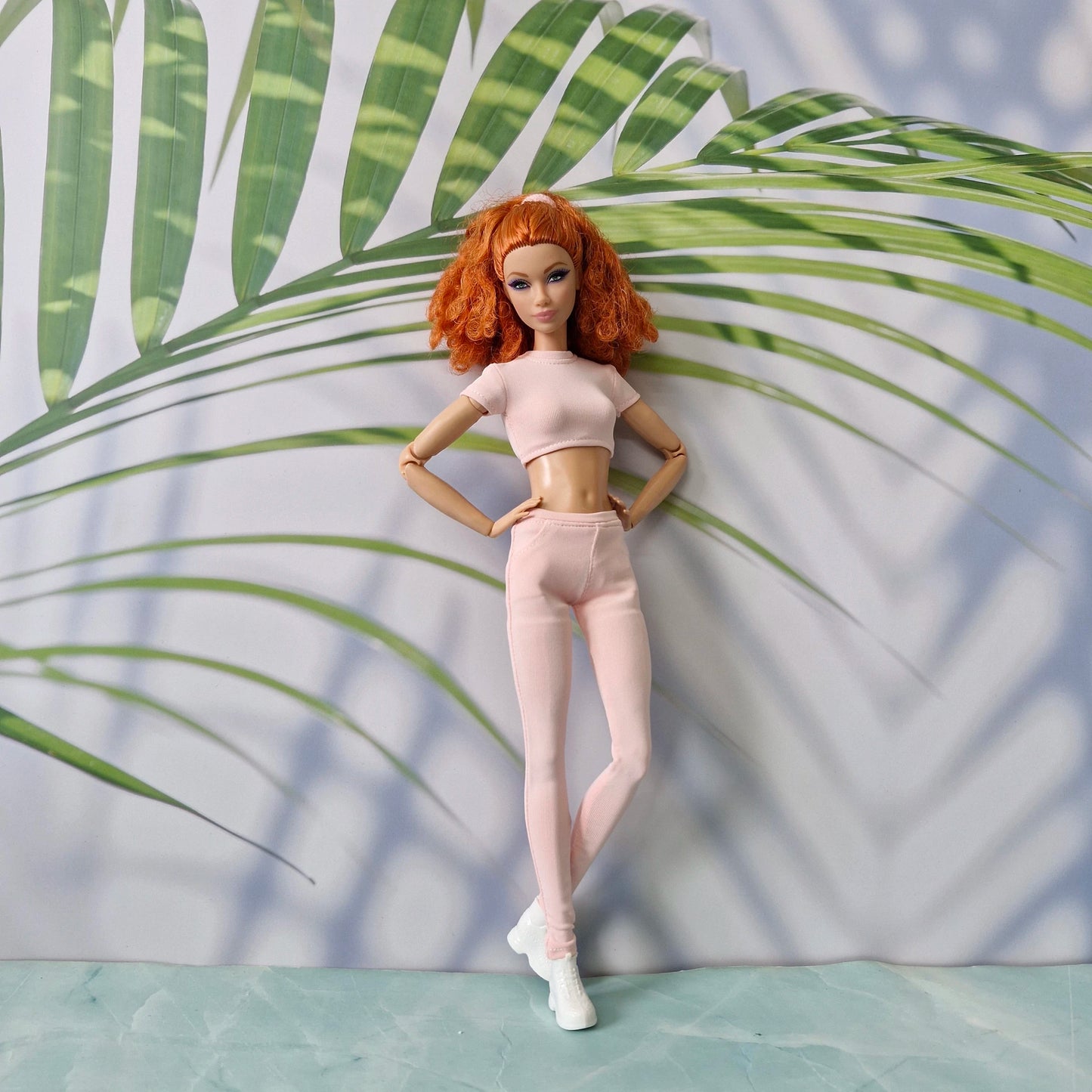 11.5 inch doll posing in a light pink ribbed crop top and high-waisted pants designed for Barbie.