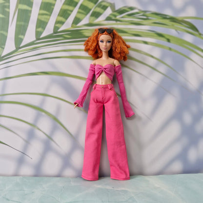 Red-haired Barbie doll wearing a dark pink off-shoulder long-sleeve top and pink wide-leg pants.