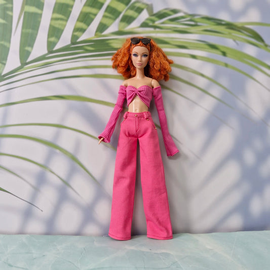 Red-haired Barbie doll wearing a dark pink off-shoulder long-sleeve top and pink wide-leg pants.