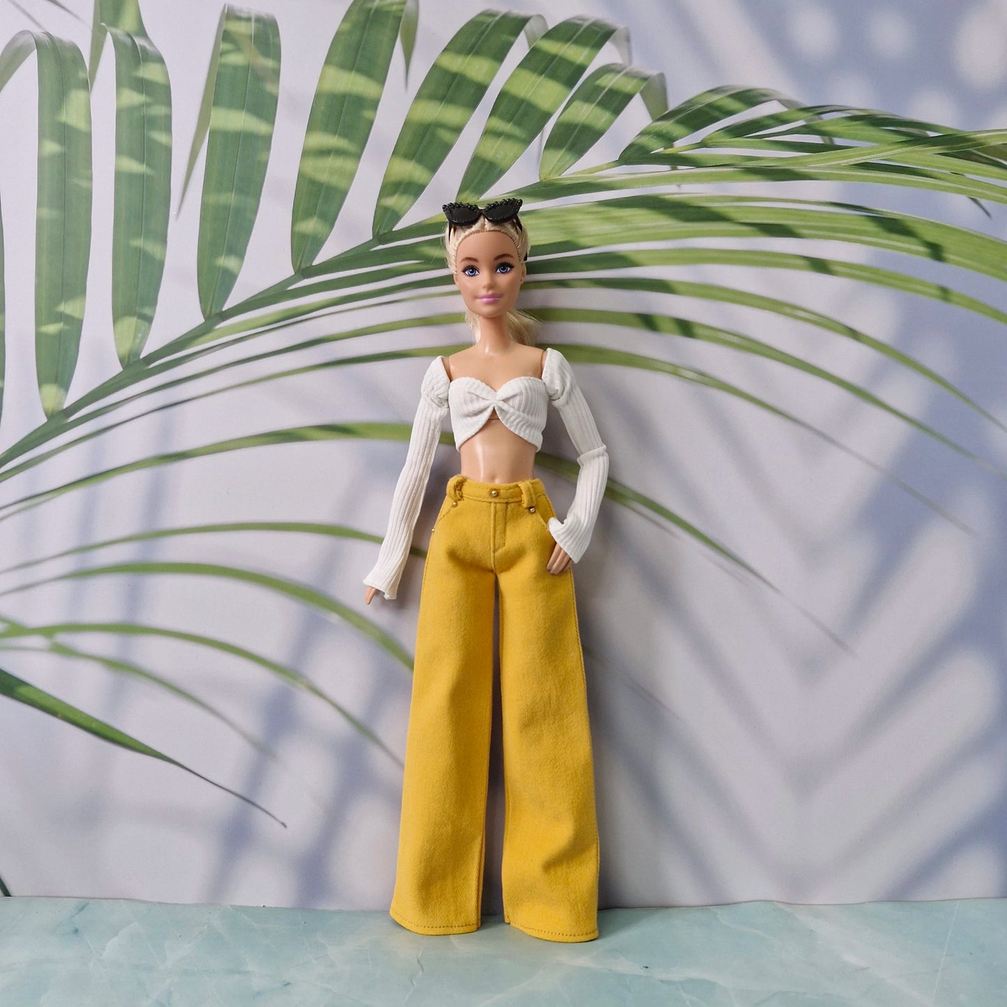 Barbie doll showcasing a white off-shoulder top paired with yellow wide-leg trousers.