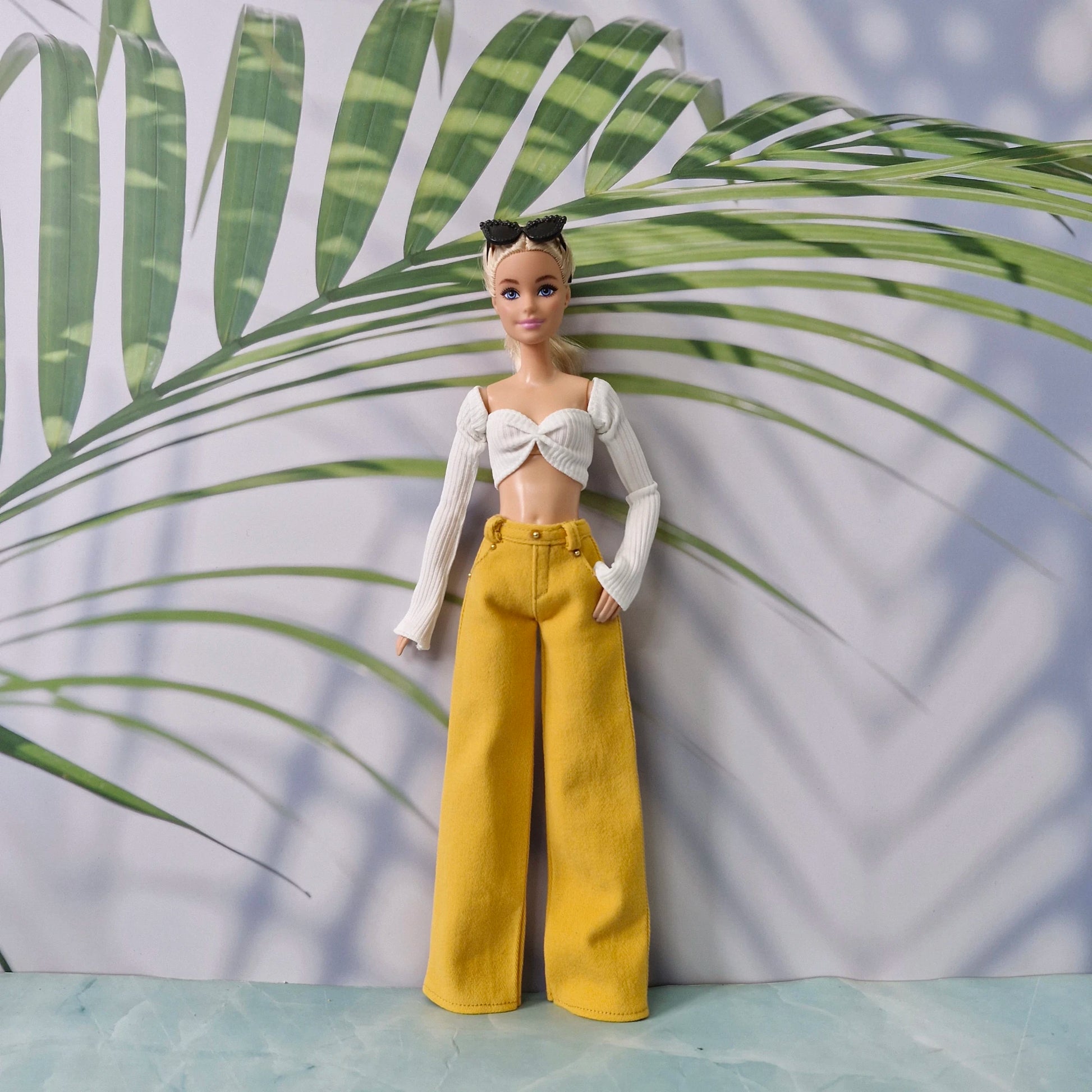 Barbie doll showcasing a white off-shoulder top paired with yellow wide-leg trousers.
